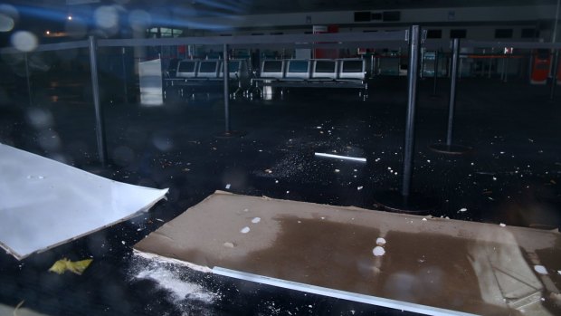Pieces of ceiling sit in flooded water at the check-in hall.