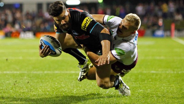 Losses piling up: Panthers winger Josh Mansour scores a try despite the tackle of Manly's Jake Trbojevic during Penrith's win on the weekend.
