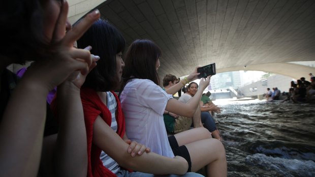 A young woman takes a photograph with a smartphone at Cheonggye Stream in Seoul, South Korea.