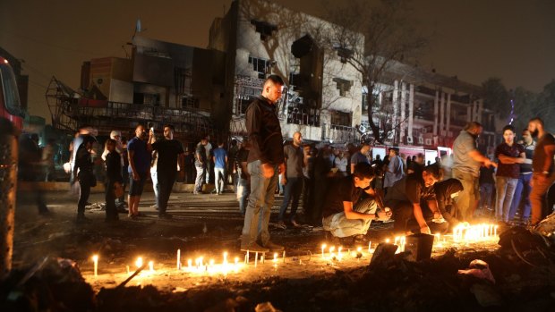 People light candles at the scene of a massive car bomb attack in Karada, Baghdad.