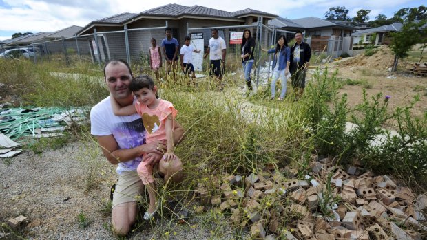 Neighbours say this abandoned building site in Crace is an "accident waiting to happen". At front are Ivan Coric and his daughter,
Katija. At rear from left, Nethmi, Kaveen, Deshan and Kanchana
Marasinghe, Anisa Coric, Rachel Huang and Yuandong Zhong.