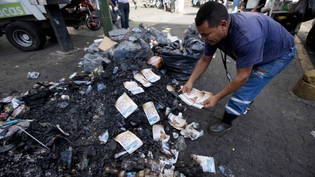 A man arranges opposition flyers allegedly burnt by government supporters in the Catia neighbourhood, Caracas. A battle was fought in a busy street there on Tuesday, after a group of alleged government supporters, some armed and on motorbikes, attacked opposition supporters as they hung election posters.