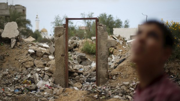 A Palestinian teen stands next to the frame of a destroyed house doorway, on which Banksy painted an image of a goddess holding her head in her hand before the door was sold.