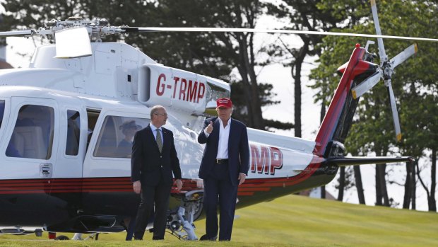 Donald Trump gestures as he disembarks from his helicopter after arriving at the Women's British Open.
