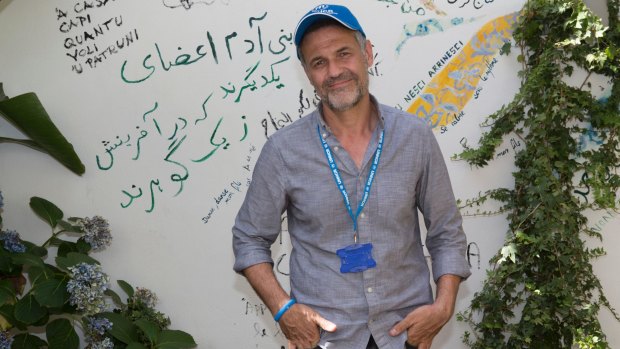 UNHCR goodwill Ambassador Khaled Hosseini beside a  poem he wrote on the walls of of the refugee-run Orient Experience restaurant in Sicily.