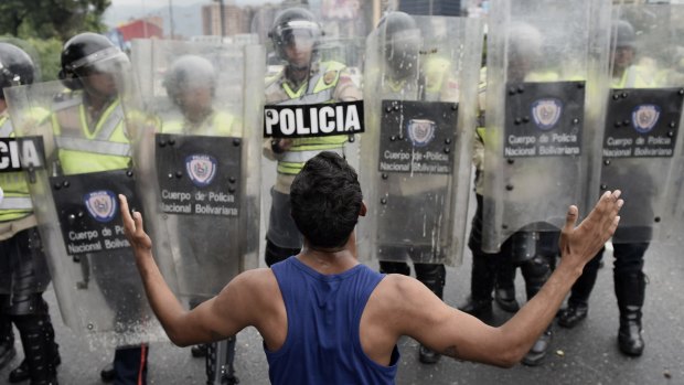A protester gestures in front of police during an opposition march in Caracas on May 11.