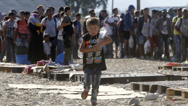 A boy carrying a bottle of water runs to board a train towards Serbia at the new transit centre for migrants on the border with Greece, near the southern Macedonian town of Gevgelija, on Thursday.