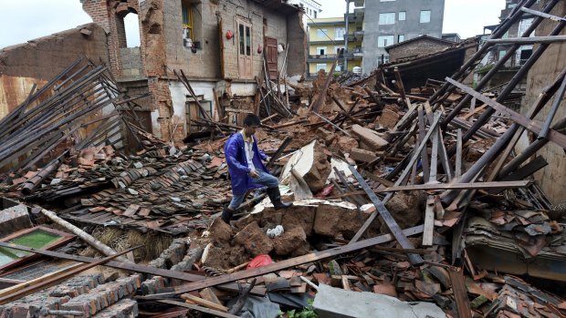 A man walks past damaged houses following Typhoon Nepartak hit Putian city in southeast China's Fujian province.