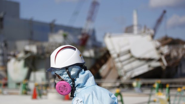 A Tokyo Electric Power Co. (TEPCO) employee walks in front of  the tsunami-crippled Fukushima No. 1 nuclear power plant on Wednesday. 