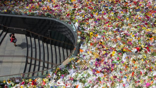 A rooftop view shows Martin Place heaving with floral tributes. 
