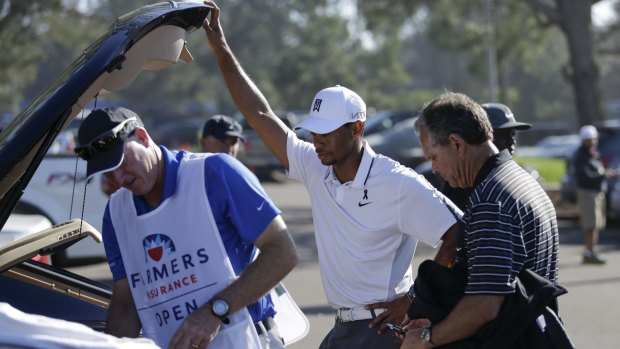 Tiger Woods (centre) loads his car after withdrawing during the first round of the Farmers Insurance Open golf tournament in San Diego on February 5, 2015.