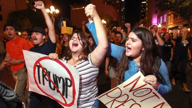 Jocelyn Rodriguez, 20, centre, and her sister Michelle Rodriguez, 16, hold hands as they and about 300 other people march in San Diego to protest Donald Trump's presidential election victory. 