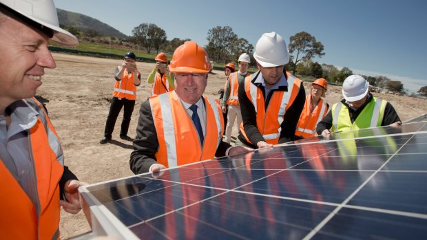 ACT Greens MLA Shane Rattenbury, Planning Minister Mick Gentleman and Daniel Radford lifting panels at the Williamsdale solar farm.