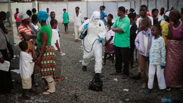 A medical worker sprays people being discharged from the Island Clinic Ebola treatment center in Monrovia, Liberia.
