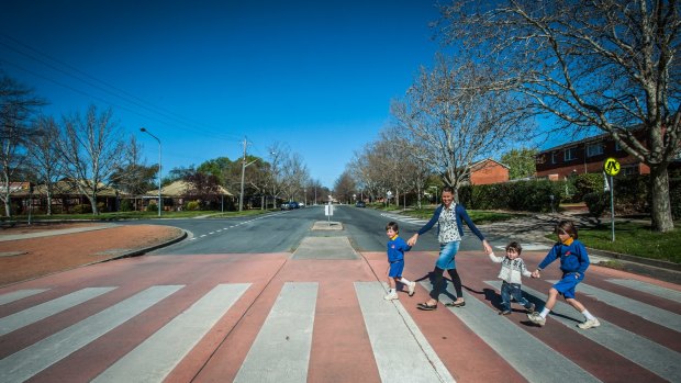 Mia Swainson of O'Connor and sons Xavier, 5, Tasman, 2, and Ashwyn, 7, cross the road at Lyneham Primary, in 2016.