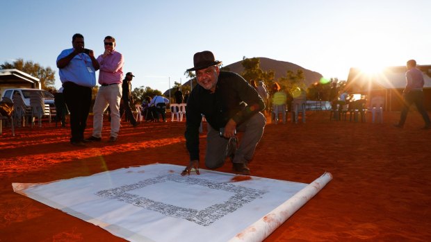 Noel Pearson signs the canvas upon which the Uluru statement was painted. The Turnbull government rejected the statement's recommendations.
