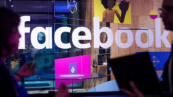 Conference workers speak in front of a Facebook demo booth.