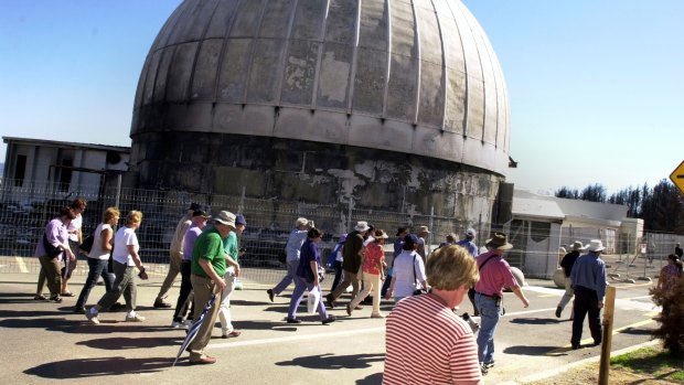 Visitors pass the destroyed 74 inch telescope at Mt Stromlo Observatory when the blackened mountain was opened for the first time after the firestorm. 