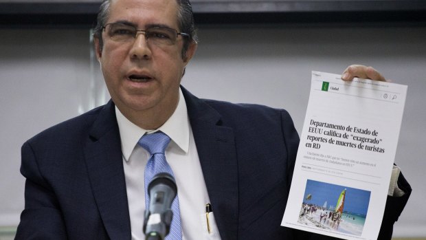 The Minister of Tourism of the Dominican Republic, Francisco Javier Garc­ia, holds a copy of an online article in a local paper saying the US State Department considers recent reports on tourists' deaths to be exaggerated.