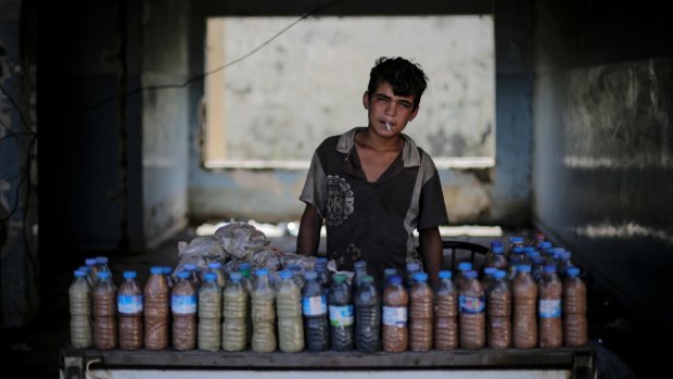 Abdul Aziz, 15, smokes a cigarette while waiting for customers to buy the mud from a sulphur well near the Hamam Alil spa south of Mosul, Iraq on Thursday, April 27, 2017. The mud is supposedly healthy for the skin.