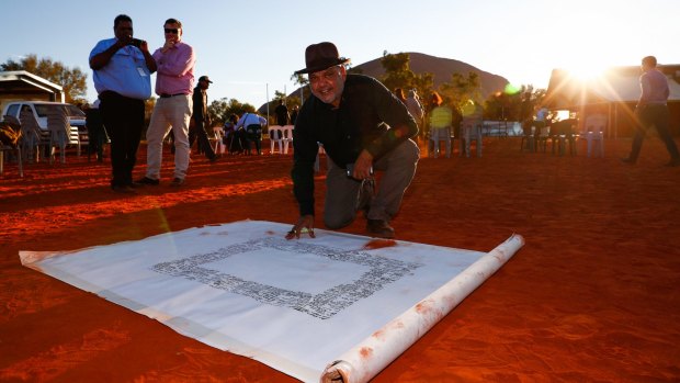Noel Pearson signs the canvas last week on which the Uluru statement will be painted.