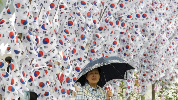 A South Korean woman walks by national flags hanging on trees in Seoul to celebrate the 70th anniversary of Independence Day in August. 