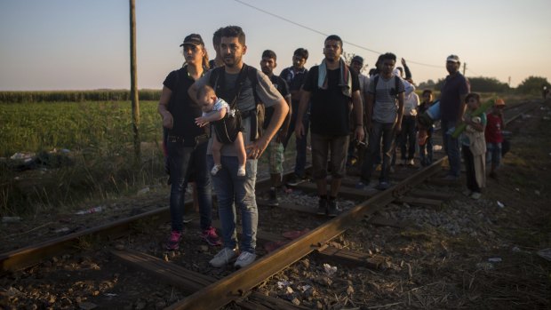 Syrian refugees walk across railways tracks next to the Serbian town of Horgos to cross the border and enter Hungary. 