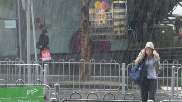 A pedestrian is caught out as heavy rain hits the CBD on Monday morning.