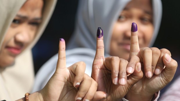 Women show their ink-stained fingers after voting during the runoff election in Jakarta.