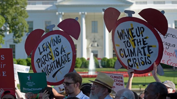 Climate protesters gather outside the White House against Trump's decision.