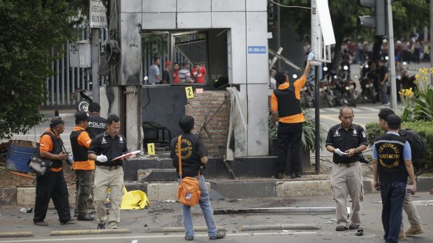 Police officers examine a police post where an explosion went off. 