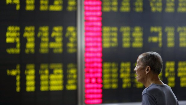 An investor watches an electronic board showing stock information at a brokerage office in Beijing, China.