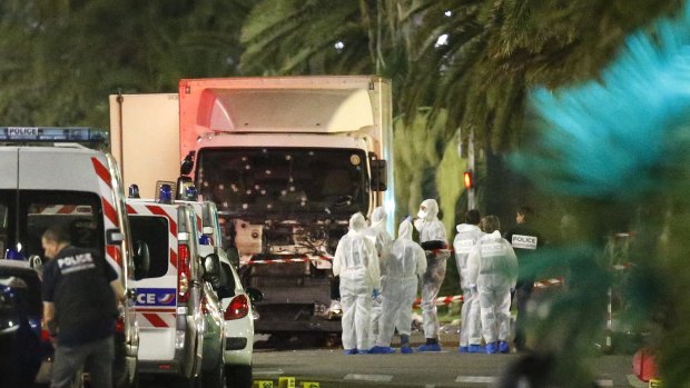 French police forces and forensic officers stand next to a truck that ran into a crowd in Nice.