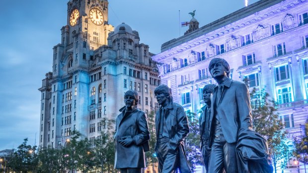 A life-size statue of The Beatles stand outside the "Three Graces" buildings.