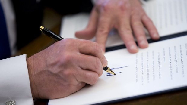 US President Donald Trump shows off his magnificently large hands as he signs one of five executive orders related to the oil pipeline industry in the Oval Office of the White House in Washington, DC.