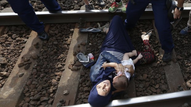 A woman lies on the track with a baby as she is detained in the Hungarian town of Bicske.