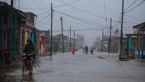Residents ride their bikes through flood waters in Caibarien, Cuba