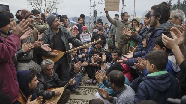 Migrants sing and clap during a protest at a makeshift camp at the northern Greek border station of Idomeni.
