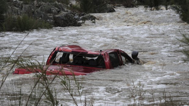 The ute driven by the Canberra man remains partially submerged in the swollen river.