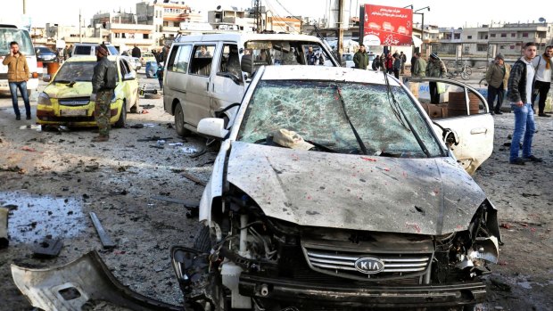 Syrian citizens gather around cars destroyed by the Islamic State bombs.
