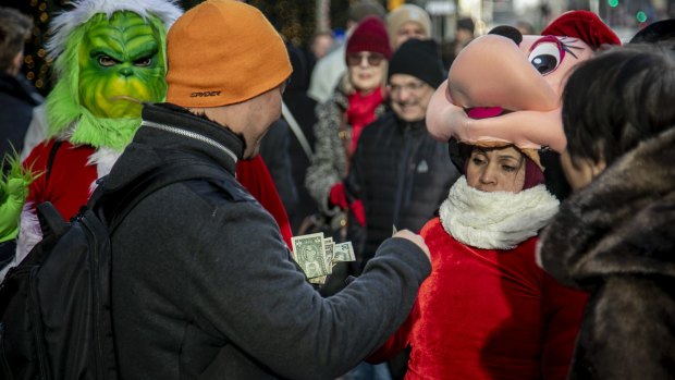 Costumed Grinch and Minnie Mouse performers receive tips after posing for photos near Rockefeller Center.