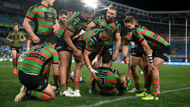 Concerned: Souths players gather around Johnston after he injured himself scoring his third try.
