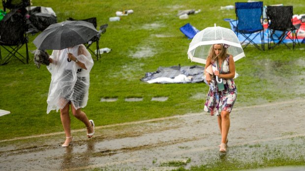 Women ake shelter from the weather at Flemington on Thursday.