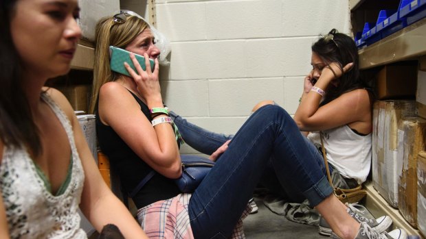 Women make phone calls while taking shelter inside the Sands Corporation plane hangar during the Las Vegas shooting.