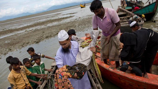 A Bangladeshi volunteer carries a Rohingya Muslim woman off a boat after she arrived with a group of other Rohingya at Teknaf, Bangladesh on Friday.