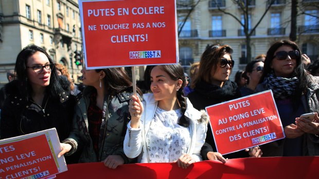 Sex workers hold signs reading "Prostitutes are angry. Don't touch our customers" during a protest before the new bill against prostitution and sex trafficking passed in Paris on Wednesday.
