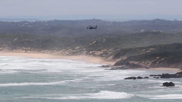 A search and rescue helicopter hovers over waters off Cape Schanck on Saturday.