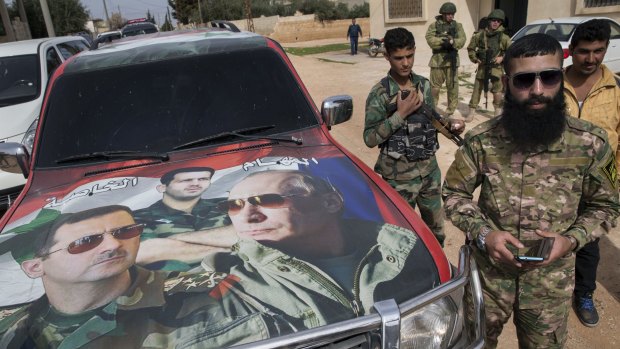 Soldiers in Maarzaf, Syria, stand by a car painted with the faces of Syrian President Bashar al-Assad, left, his brother, General Maher al-Assad, centre, and Russian President Vladimir Putin.