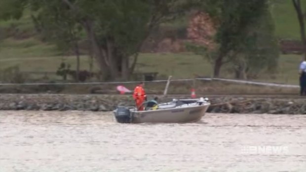 A boat searches the Tweed River for the car which slid off the road about 1.40pm.