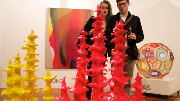 A couple looks at a Tracy Sarroff piece at the Arc One gallery stand during the 2014 Melbourne Art Fair.